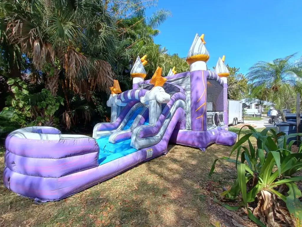 Bounce house rentals in North Fort Myers, FL set up in a backyard with a purple castle combo and slide