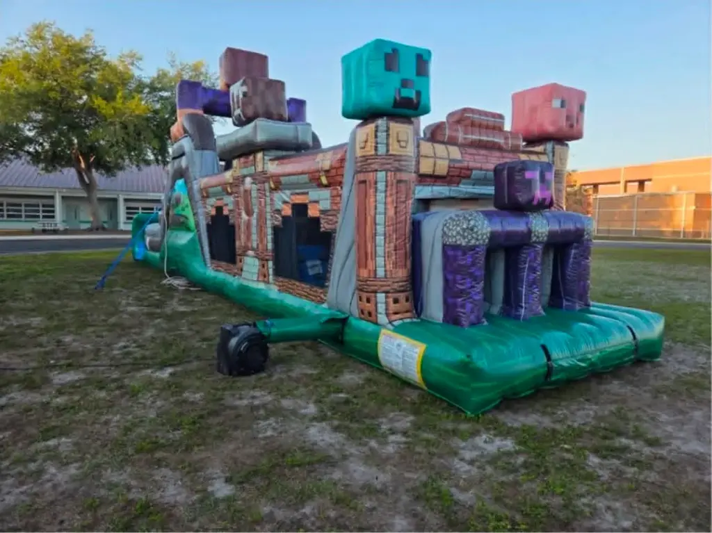 Party rentals Cape Coral FL — Minecraft themed inflatable obstacle course set up on a school campus grass field