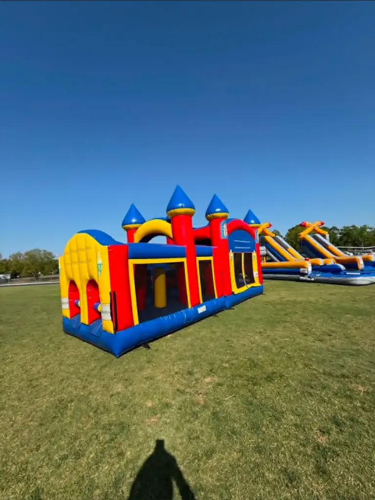 Red yellow and blue castle-themed inflatable obstacle course rental set up on grass by Family First Events and Rentals in North Fort Myers FL