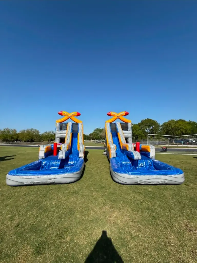 Two matching crisscross inflatable water slides with splash pools set up side by side on a field, available for party rentals in North Fort Myers FL
