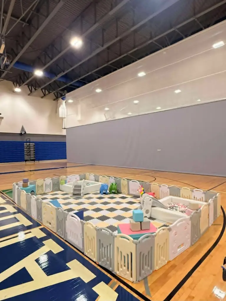 Indoor soft play area with foam mats ball pit and toddler toys set up in a gymnasium, available for party rentals in North Fort Myers FL from Family First Events and Rentals